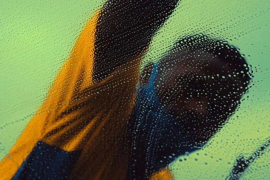 A detailed view of a hand cleaning a stovetop using a spray bottle and cloth.